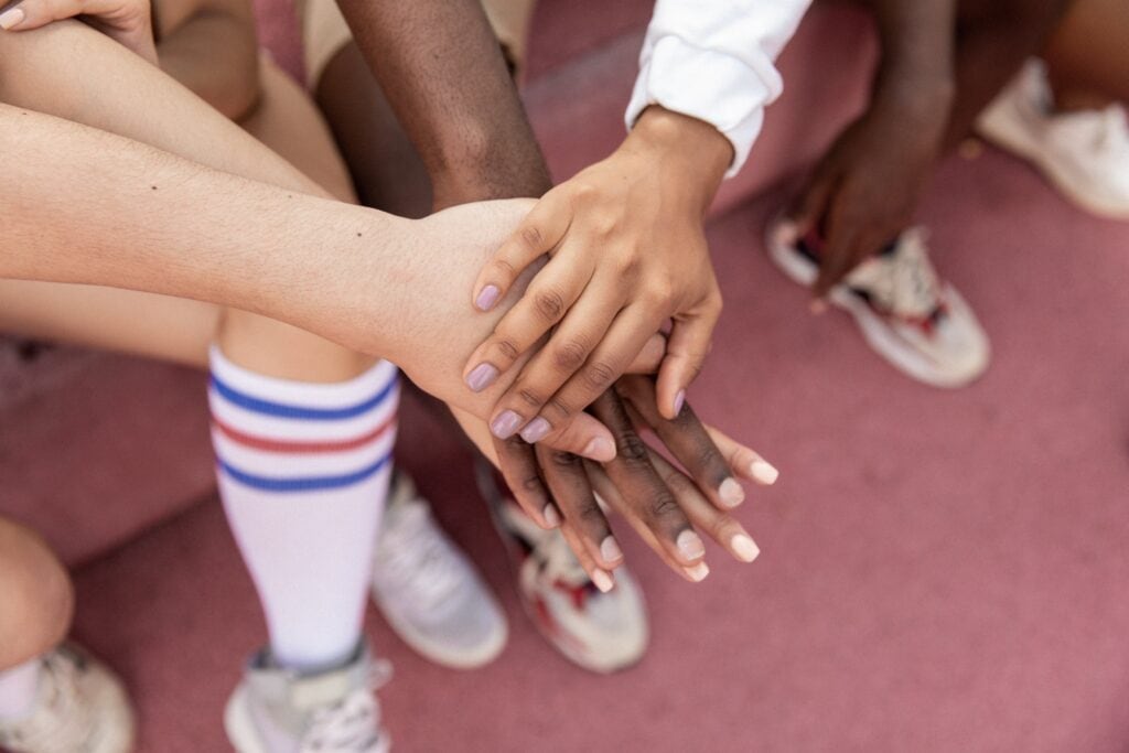 Your Child's Natural Way Of Learning (It's Not What Traditional Schools Do) 16 Four kids from different ages and different cultures holding putting their hands on top of each other.