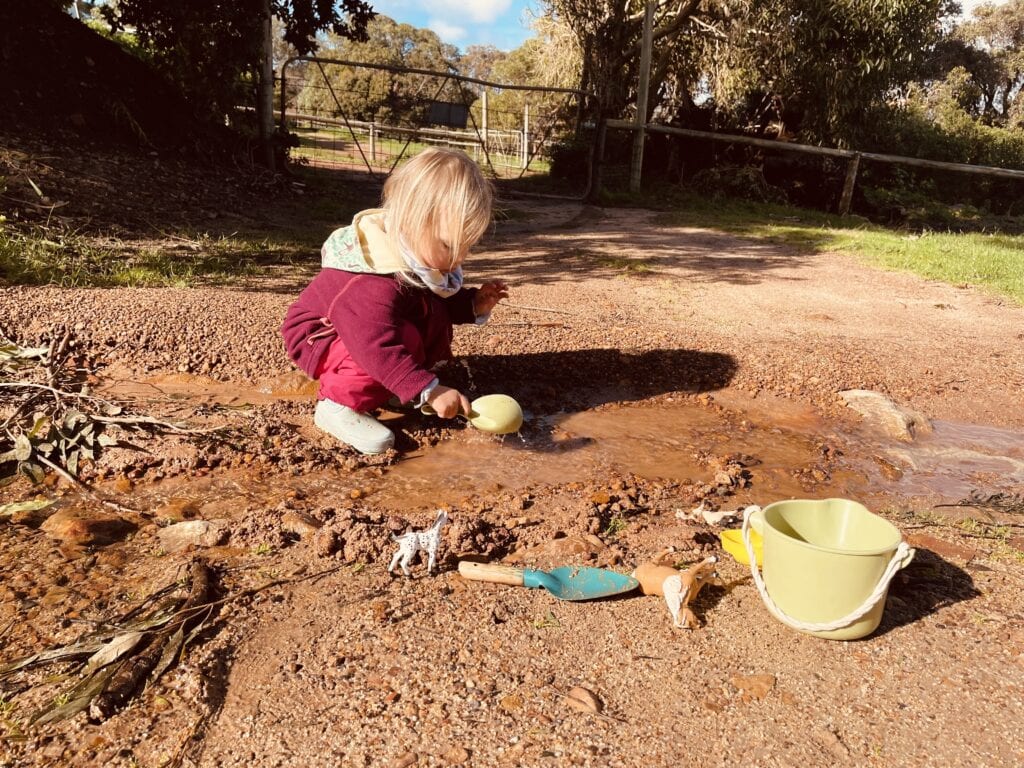 A child playing outside with water after a heavy rain.