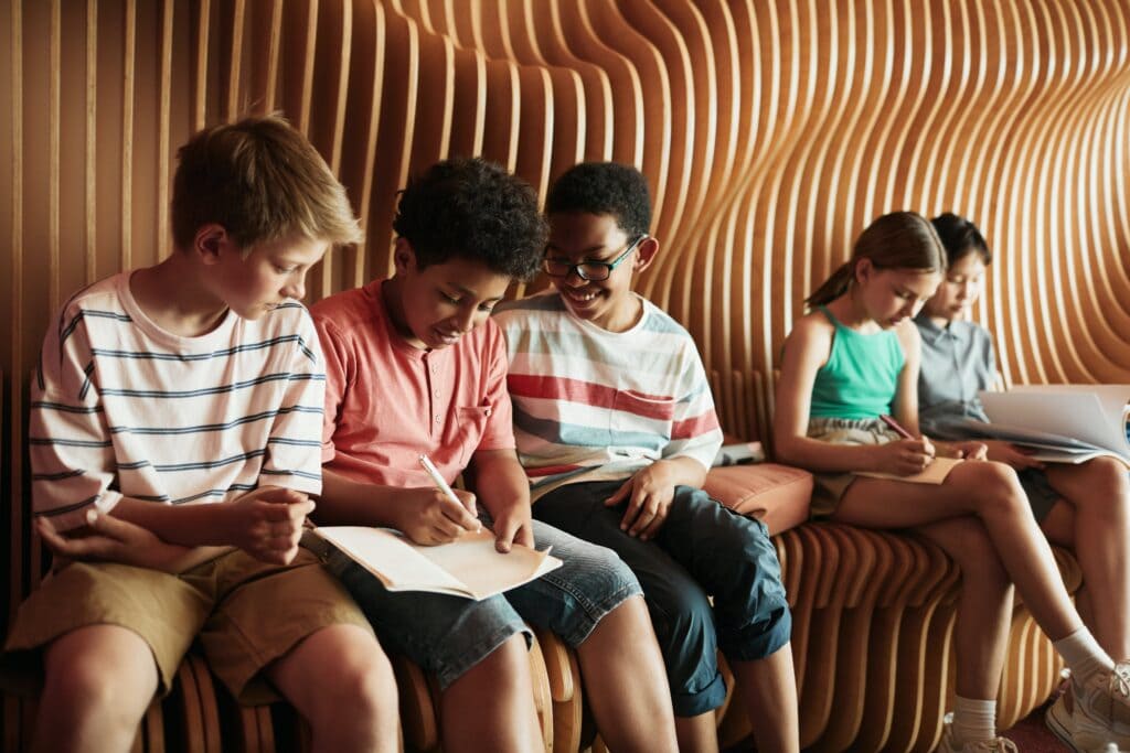 Children learning on a bench outside the classroom.