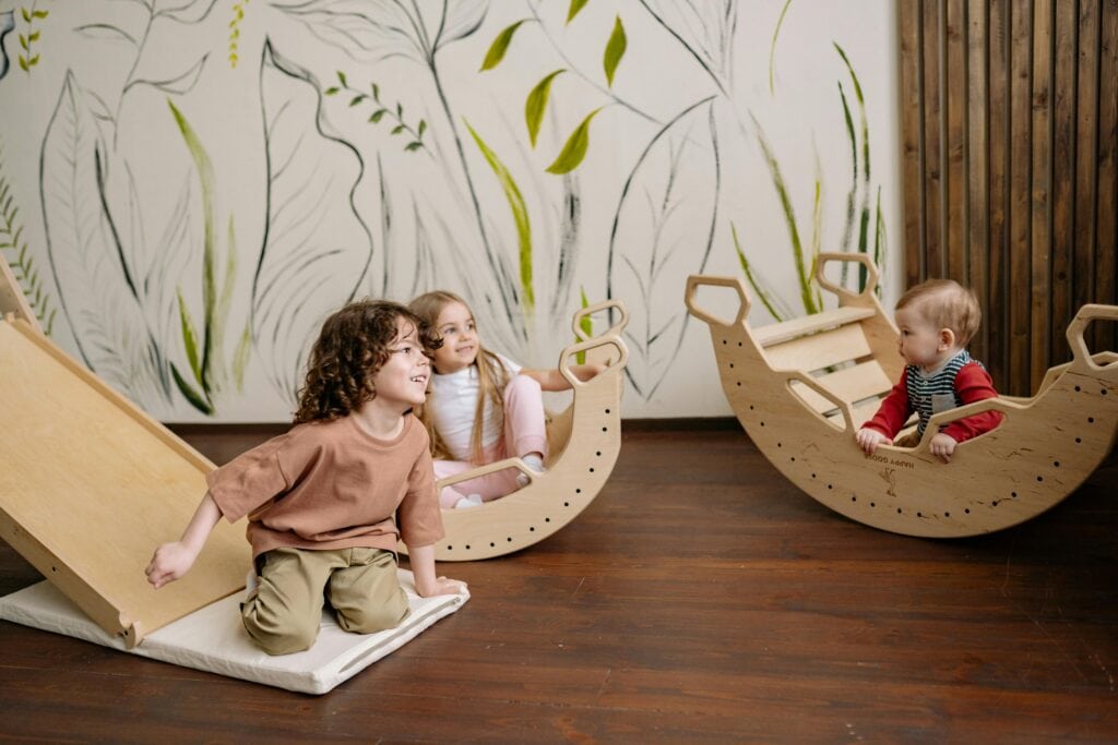 Three mixed-aged children following the playgroup at Schola Vera.
