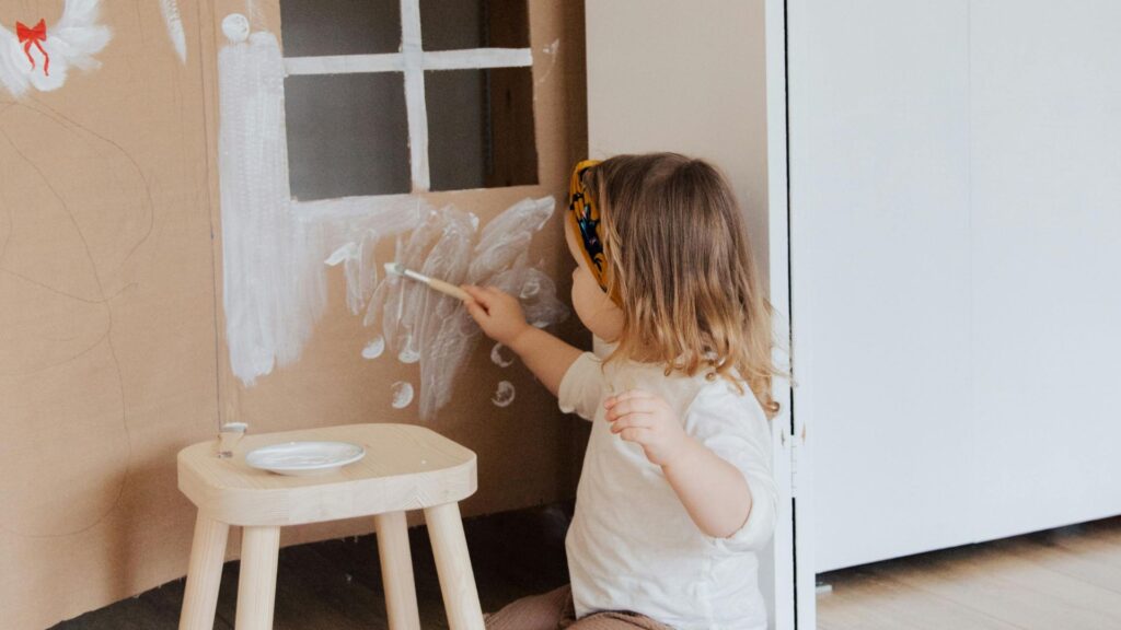 Montessori, Waldorf, or Something Different? A Parent's Guide to Educational Choices 7 A little girl painting on a cardboard wall in a Schola Vera environment.