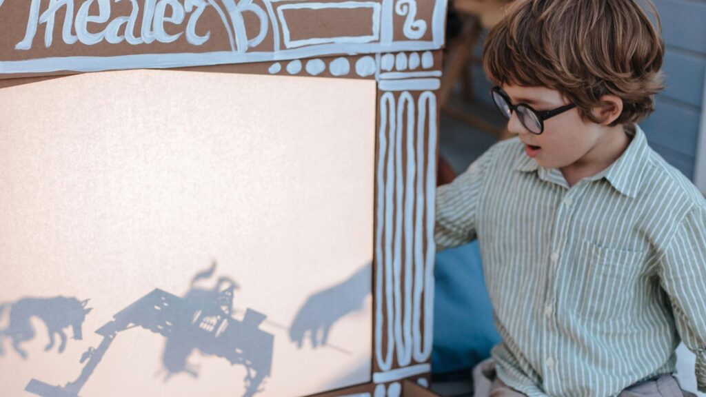 Montessori, Waldorf, or Something Different? A Parent's Guide to Educational Choices 5 A young boy is standing in front of a cardboard box with a shadow of a movie theater.